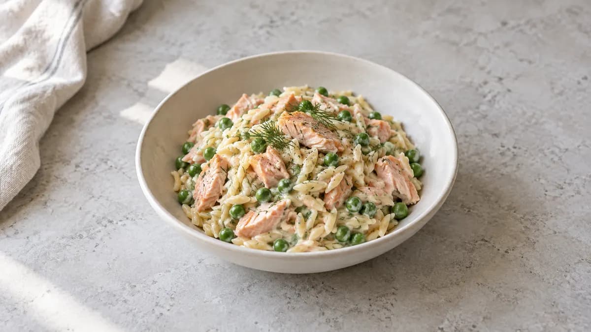 Salmon and pea orzo served in a small portion on pale stone